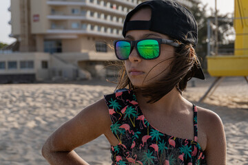 Close-up of a girl with glasses and cap on a beach