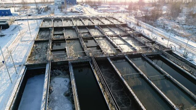 Reservoirs with processed dirty water and technological bridges at purification plant at sunset in winter bird eye view