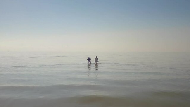 Aerial drone view of two people walking in the water at low tide in Cape Cod