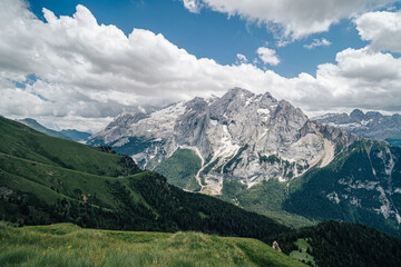 Obraz premium Summer view of Marmolada (Punta Penia), the highest peak in Dolomites, Italy. Alpine landscape of Dolomiti with a view of a glacier on Marmolada and beautiful green meadow with yellow flowers.