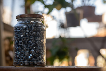 glass jar full of screw nuts with blurred background. copy space