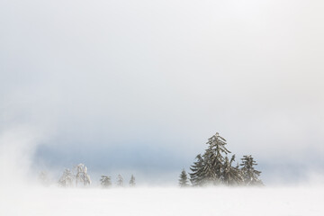Durch ein schmales Fenster im Nebel und aufgewirbeltem Schnee werden der blaue Himmel, im...