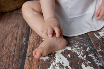 small children's feet in flour on a wooden background