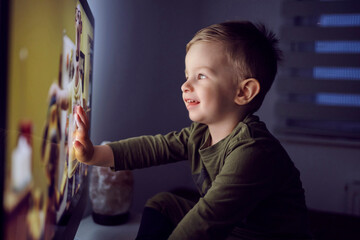 A bedtime ritual for toddlers. The boy touched the TV screen with one hand. A close-up shot of a...