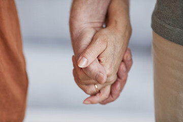 Close up of caring senior couple holding hands and walking together, copy space