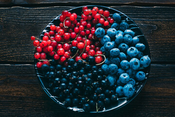 Red currant berries in a ceramic bowl on a rustic wooden background. Copy space. Dark background