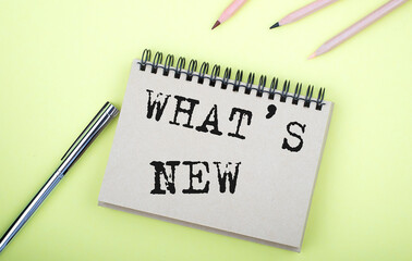 WHAT'S NEW text on the notebook with pen on yellow background