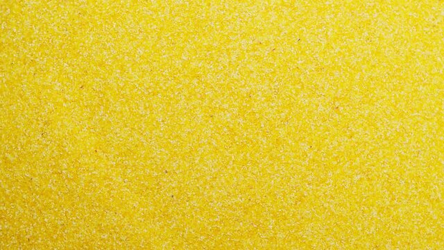 Rotating pile of polenta close-up. Shooting of cereal and groats in studio. Macro footage of pouring out the grits. Food cooking, harvest video. 