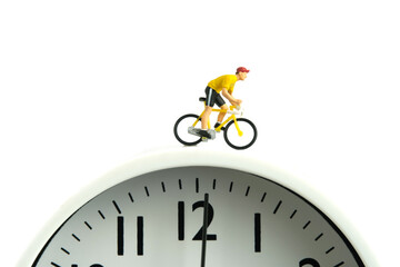 Miniature people toy figure photography. Cycling schedule concept. A biker cycling above clock,...