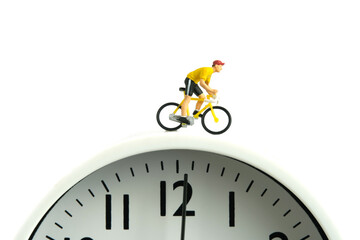 Miniature people toy figure photography. Cycling schedule concept. A biker cycling above clock, isolated on white background.