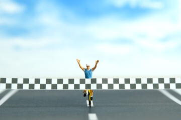 Miniature people toy figure photography. A biker with finish line, completed the bike competition,...