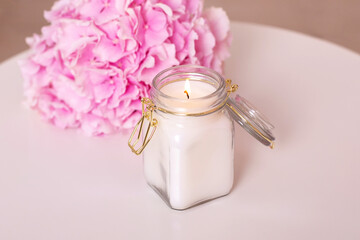 Beautiful candle light with pink peonies flowers on white table, romantic background