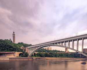 Bronx, NY - USA - July 17, 2021: Wide horizontal view of the historic High Bridge spanning the Harlem River and Highbridge Water Tower is the distance.
