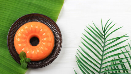Top View Mango orange pudding on black plate with mint leaf on wooden table