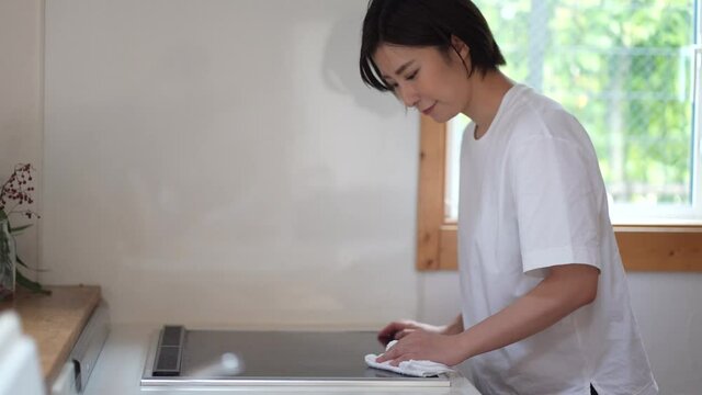 クッキングヒーターの拭き掃除をする女性