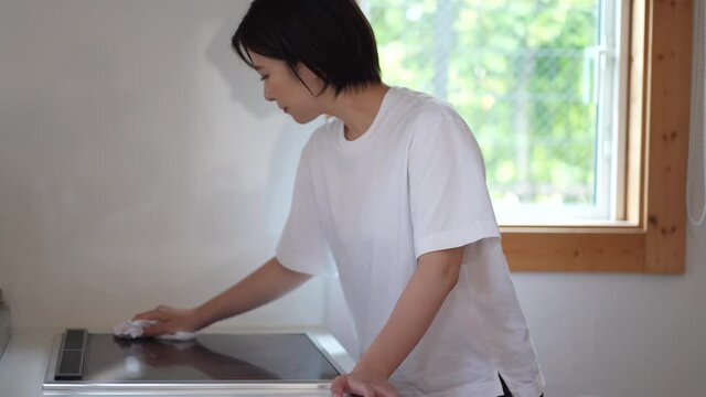 クッキングヒーターの拭き掃除をする女性