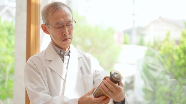 サンプル瓶を観察する医師