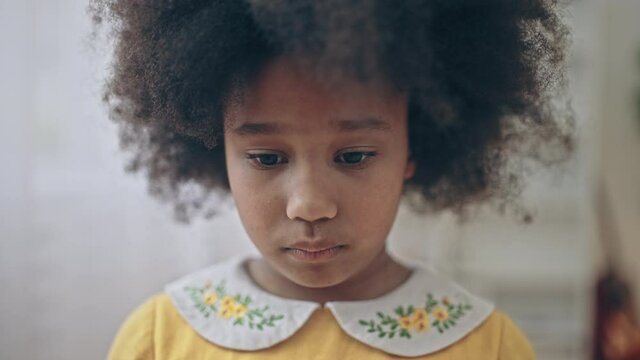 Sad lonely African-american girl with natural black hair looking into camera