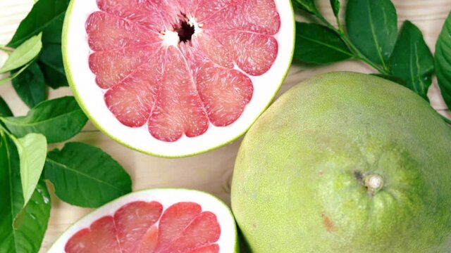 Top view Rotate Red Pomelo fruit with leaves on wooden table in garden, Red Pomelo fruit with leaves in wooden background 4k resolution.
