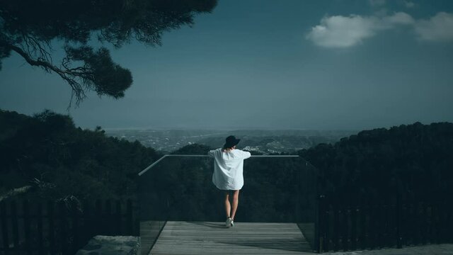 Aerial view, woman on viewpoint, looking at forest mountain landscape, view from back. Journey on island Cyprus. Troodos, Mount Olympus. Travel concepts. Terrain, open border. Drone flight