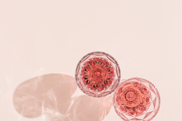 Wineglass close up, two glasses of rose wine in bright sunlight. Summer alcohol drinks concept. Pink monochrome photo