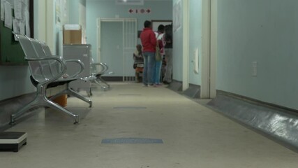 Tilt-up shot from corridor floor to patients at waiting area at a South African government hospital.