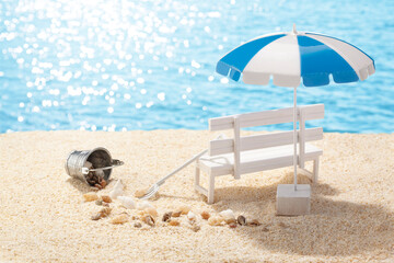 Fototapeta na wymiar 潮干狩りへ夏の砂浜と白いベンチとビーチパラソル