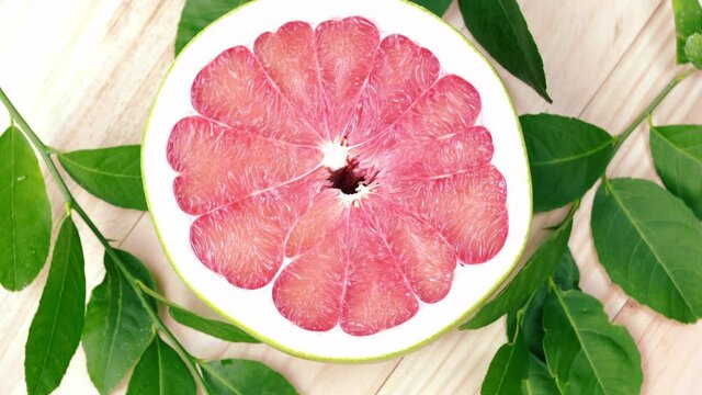 Top view Rotate Red Pomelo fruit with leaves on wooden table in garden, Red Pomelo fruit with leaves in wooden background 4k resolution.