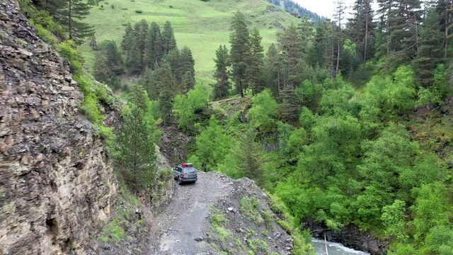 Cinematic drone shot of vehicle driving on the Abano Pass, the dangerous road to Tusheti Georgia along side the Alazani River