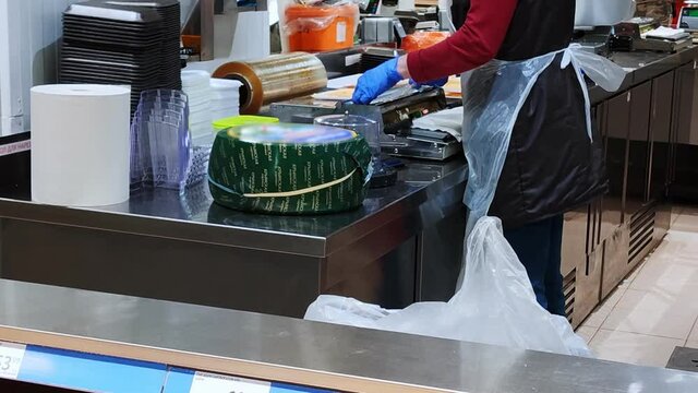 Employee packing cheese on cheese packaging machine. Industry of selling products