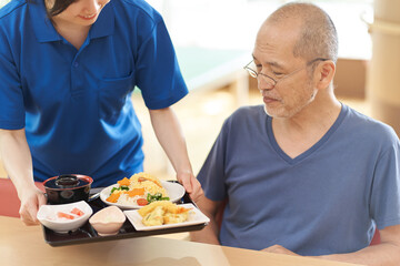 高齢者に配膳をする介護士