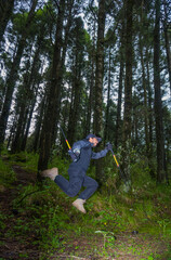 man jumping in the forest with walking sticks