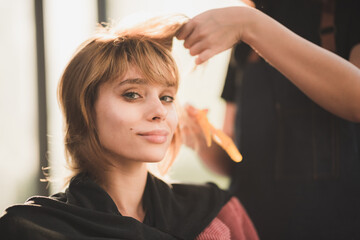 Fototapeta premium Hairdresser drying her client's hair with a hairdryer at beauty salon