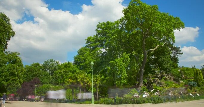 Timelapse of Parc Monceau with people, green trees and cloudy blue sky - 4k