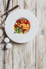 Traditional penne pasta with tomatoes, spices, Parmesan cheese and fresh basil. Dish of classic Mediterranean cuisine in a white plate with forks on a wooden background. Copy space. Top view