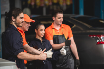 a portrait group photo of machanic team smilling in front of garage with thumb up, the professional engineer colleague in uniform, teamwork concept.