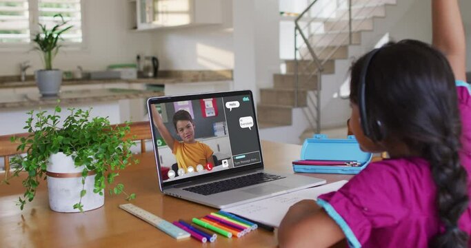 Schoolgirl using laptop for online lesson at home, with her school friend and web chat on screen
