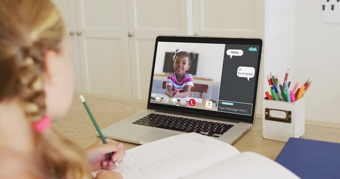 Schoolgirl using laptop for online lesson at home, with her school friend and web chat on screen