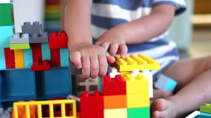 little baby hands playing with plastic toy bricks and blocks building or constructing house close-up view. education leisure activity lifestyle childhood concept - Powered by Adobe