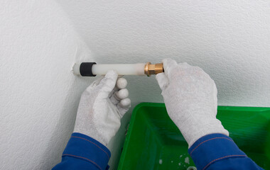 in a plastic pipe, a worker in protective gloves installs a copper adapter for plumbing