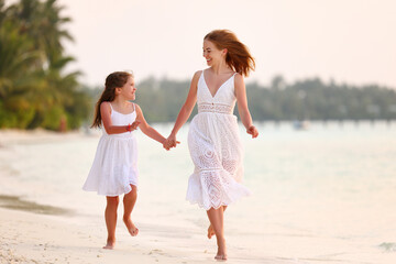 Happy family mother and daughter running in beach