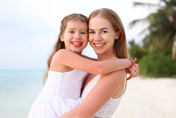 Happy mother and daughter hugging on beach