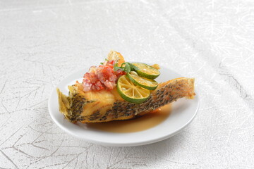 deep fried fresh grouper fish fillet in spicy and sour chilli lime sauce in white background asian halal seafood fine dining menu