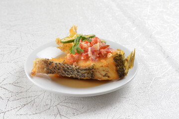 deep fried fresh grouper fish fillet in spicy and sour chilli lime sauce in white background asian halal seafood fine dining menu