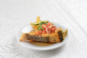 deep fried fresh grouper fish fillet in spicy and sour chilli lime sauce in white background asian halal seafood fine dining menu