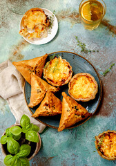 Mini quiches on a blue plate with glass of cold tea. Flaky dough pies. Samosa, samsa meat stuffed...