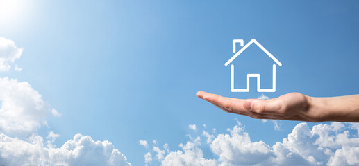 Naklejka premium Male hand holding house icon on blue background. Property insurance and security concept.Real estate concept.Banner with copy space.