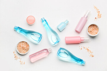 Bottles with different cosmetic products and sea salt on light background