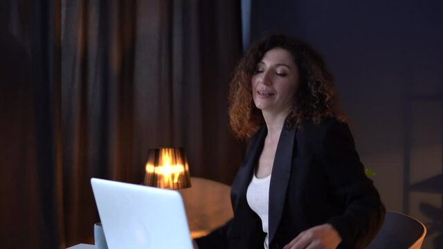 Girl is ancing celebrating the completion of the late work. Happy winner. Beautiful business woman in a business suit is working late in the office.