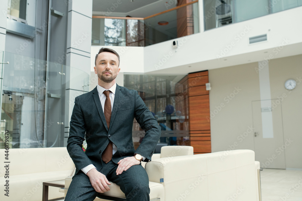 Canvas Prints portrait of young businessman in suit looking at camera while sitting on the sofa in office hall